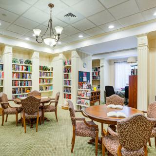 A cozy library interior with bookshelves, tables, and chairs for reading.