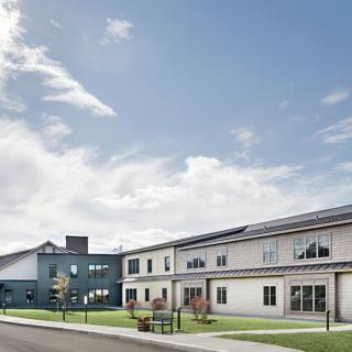 A modern building with a spacious lawn under a blue sky with scattered clouds.