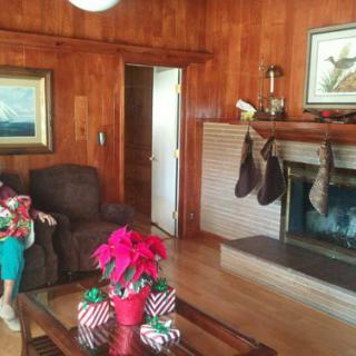 Cozy living room decorated for the holiday season with stockings hung by the fireplace and a poinsettia centerpiece.