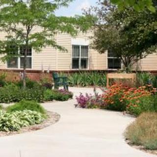 A beautifully landscaped garden with a winding pathway surrounded by vibrant flowers and lush greenery in front of a building.