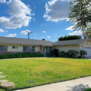 A suburban house with a well-maintained lawn under a partly cloudy sky.