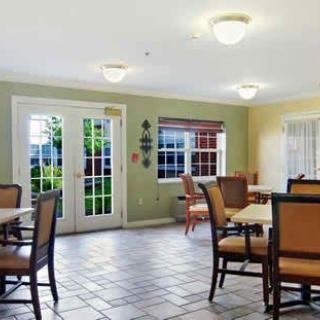 A cozy dining area featuring multiple tables and chairs, with large windows providing ample natural light.