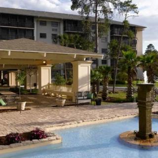 A scenic view of a hotel resort with a fountain and palm trees in the foreground.