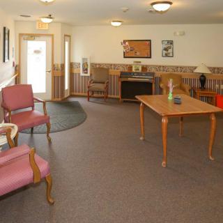 A cozy room with seating and a wooden table, featuring soft lighting and decorative elements.