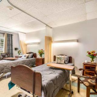 A well-lit hospital patient room featuring two beds, designed for comfort and care.