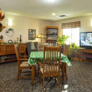 A cozy living room with a dining table and chairs, decorated with plants and ornaments.