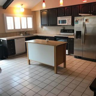 A modern kitchen with a central island, dark cabinets, and stainless steel appliances.
