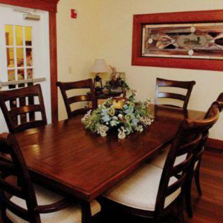 A cozy dining room with a wooden table and chairs, featuring a flower arrangement centerpiece.