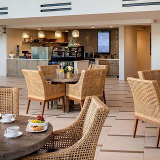A modern cafe interior with comfortable wicker seating and a well-equipped counter.
