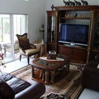 A cozy living room with elegant wooden furniture and a large television.