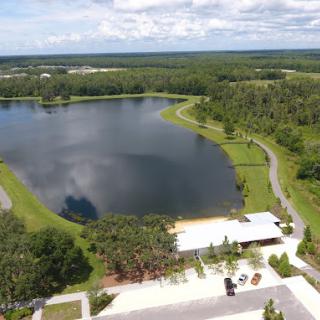 Aerial view of a serene lake surrounded by lush greenery and a nearby building.