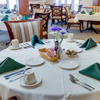 A neatly set dining table in a restaurant with green napkins and elegant decor.