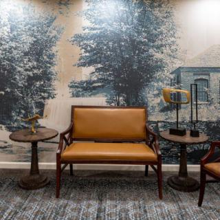 A cozy seating area with vintage-style furniture and a scenic wall mural.