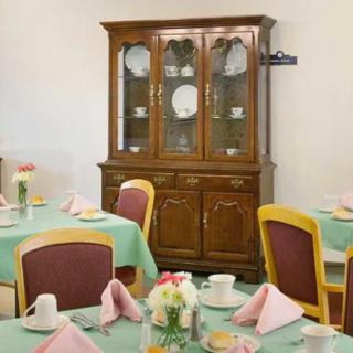 A dining area featuring a china cabinet with neatly arranged table settings and floral centerpieces.