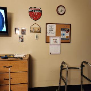 A room featuring a television, a walker, and various decorative items on the wall.