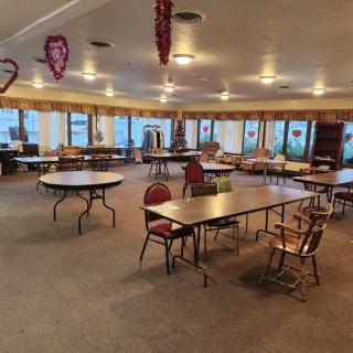 An empty event space with tables and chairs arranged in a carpeted room, decorated with hanging ornaments.