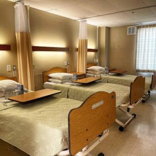 A view of a patient room in a hospital featuring several beds and a calm environment.