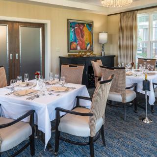 An elegantly set dining room with neatly arranged tables, chairs, and decorative artwork on the walls.