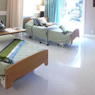 A hospital room with two beds and natural lighting.