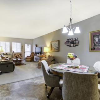 A cozy living and dining area with comfortable seating, a television, and decorative artwork.