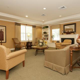 A cozy living room with beige furniture, a fireplace, and warm lighting.