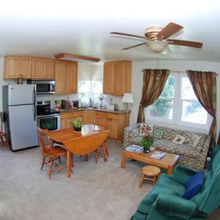 A cozy open-plan kitchen and living room with wooden cabinetry, a dining table, and comfortable seating.