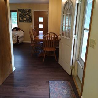 A hallway leading to a dining area with wooden chairs and an open door.