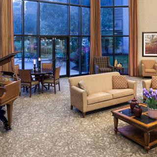 A spacious living room featuring elegant furniture, a grand piano, and large windows allowing natural light to fill the space.