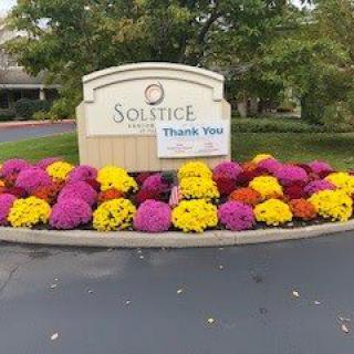 A colorful arrangement of flowers surrounds a welcome sign with a 'Thank You' note.
