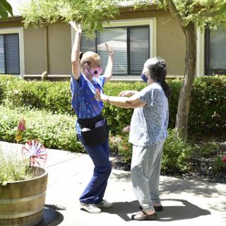 Two women enjoy a joyful dance outdoors, celebrating together.