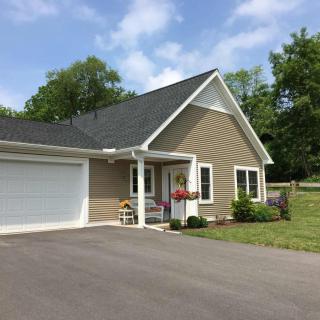 A suburban house with a driveway and attached garage, surrounded by greenery.