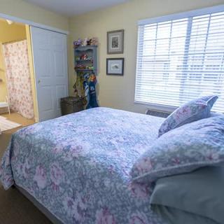 A cozy bedroom with floral bedding and bright natural light from the window.