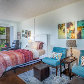 A cozy and modern bedroom featuring colorful artwork, comfortable seating, and ample natural light.