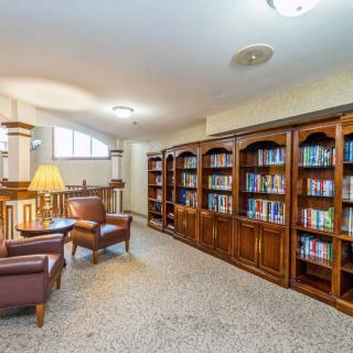 A cozy library with wooden bookshelves and comfortable armchairs.