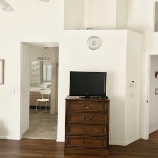 A modern living space featuring a wooden dresser and television against white walls.