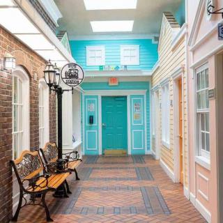 A charming indoor hallway with vintage street lamps, benches, and colorful house-like facades.