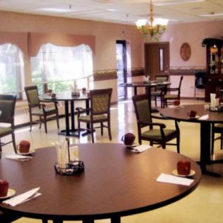An empty dining area with neatly arranged tables and chairs, featuring warm lighting and soft decor.