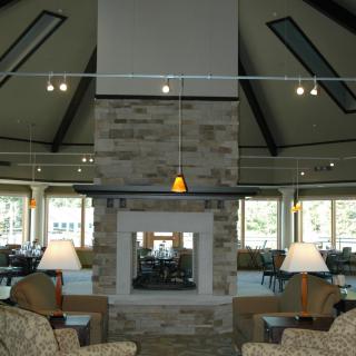 A modern living room interior with a central stone fireplace and comfortable seating.