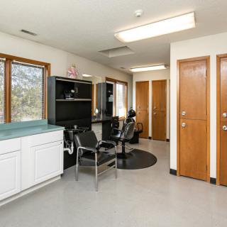A brightly lit salon interior with styling chairs and mirrors.