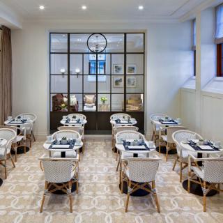A modern dining area with neatly arranged tables and chairs, featuring elegant decor.