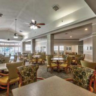 Spacious dining area with multiple tables and chairs, featuring ceiling fans and ample natural lighting.