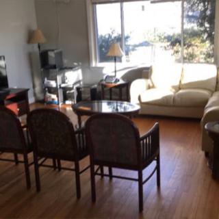 A cozy living room featuring a sofa, chairs, and a table near a large window with natural light.