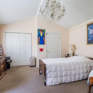 A cozy bedroom featuring a single bed, chandelier, and artwork on the walls.