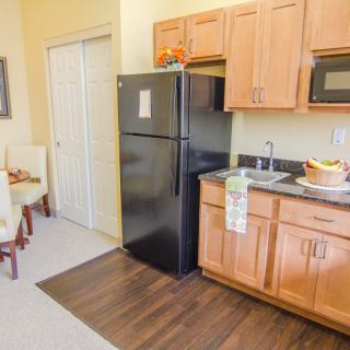A modern kitchen with wooden cabinets, a black refrigerator, and a microwave.