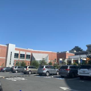 A sunny day at a shopping center parking lot, showcasing various vehicles against a clear blue sky.