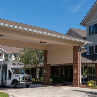 A bus parked under the entrance of a retirement home on a sunny day.