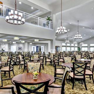 A spacious and elegantly designed dining hall featuring numerous tables and chairs under grand chandeliers.