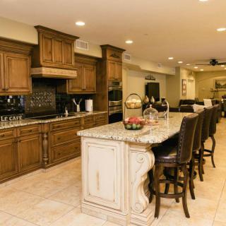 A spacious kitchen with wooden cabinets, a granite-topped island, and seating area.