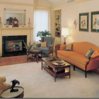 A cozy living room with a warm color palette, featuring a fireplace and comfortable seating arrangement.