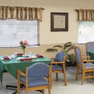A cozy dining room with neatly arranged tables and chairs, adorned with floral decorations.